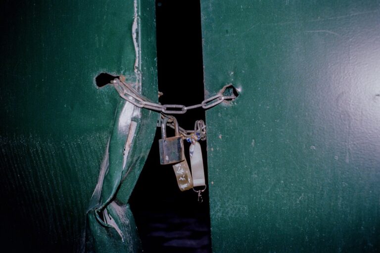 Puerta verde con una cadena y candados: abogado de allanamiento de morada en Madrid
