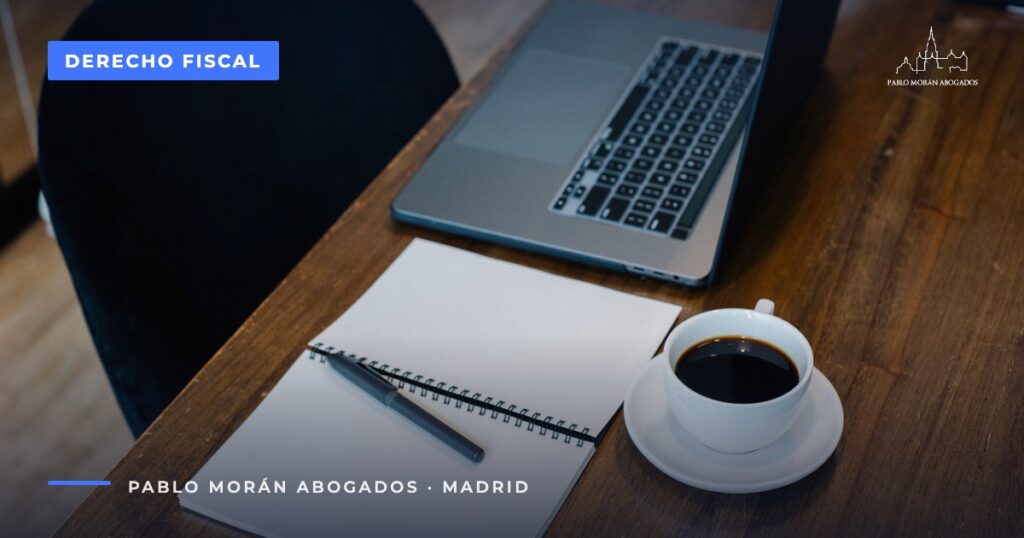 Portátil, cuaderno y café sobre una mesa de madera: calendario fiscal del autónomo, abogado fiscalista en Madrid