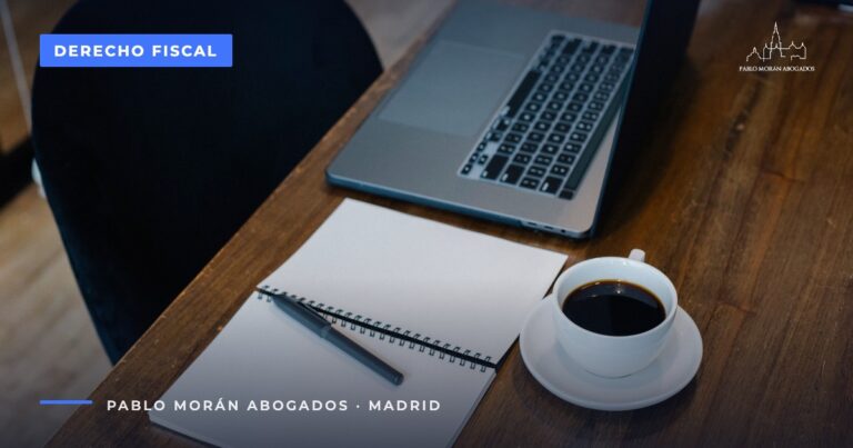 Portátil, cuaderno y café sobre una mesa de madera: calendario fiscal del autónomo, abogado fiscalista en Madrid