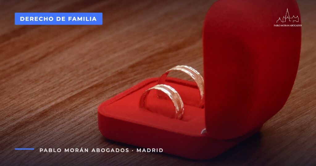 Estuche rojo con alianzas sobre una mesa de madera: capitulaciones matrimoniales y régimen económico, abogado de familia en Madrid