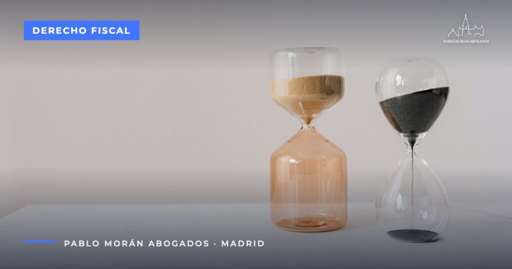 Dos relojes de arena sobre una mesa blanca: prescripción tributaria, abogado fiscalista en Madrid